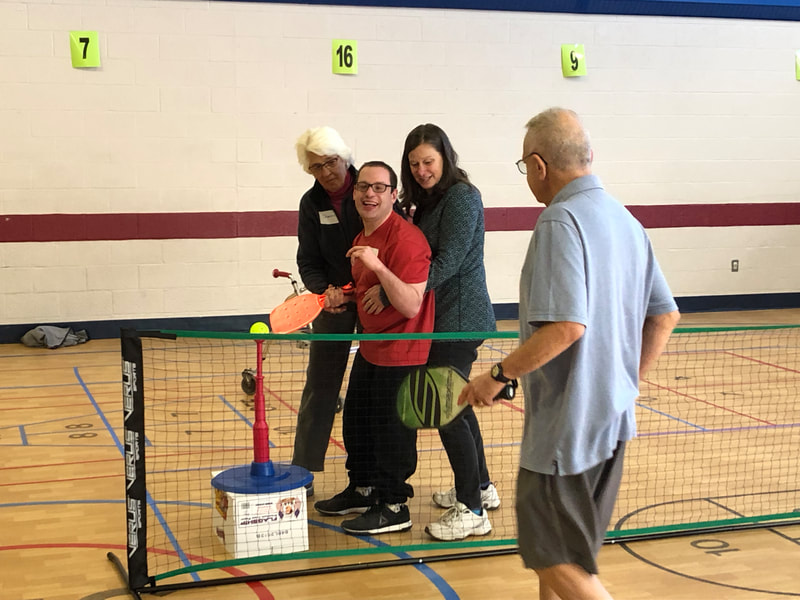 student and volunteers work together at pickleball clinic